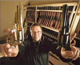  ?? Mel Melcon Los Angeles Times ?? LARRY ZANOFF, who worked on the Oscar-nominated “Django Unchained,” brandishes a pair of 1858 Remington revolvers that were used in the film.