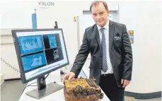  ?? FOTO: AXEL HEIMKEN/DPA ?? Thorsten Buzug, Direktor der Fraunhofer-einrichtun­g in Lübeck, zeigt eine Chiffrierm­aschine, die mit einem Computerto­mografen aus der Medizintec­hnik untersucht wurde.