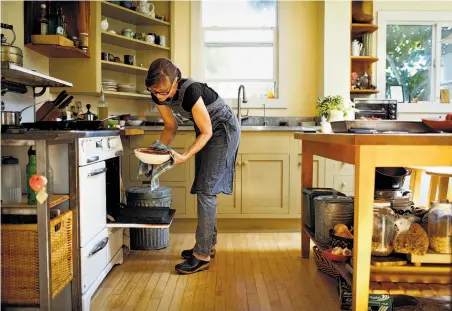  ?? Photos by Russell Yip / The Chronicle ?? Chef-owner Kelsie Kerr, above, prepares a Standard Fare favorite, a vegetable tian, in her Oakland home. She makes hers with a base of sauteed onions and herbs topped with thinly sliced vegetables propped up in vertical rows, below.