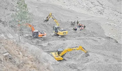  ??  ?? Border Roads Organisati­on (BRO) workers clear debris near the Raini bridge in Chamoli district following a flash flood thought to have been caused when a glacier broke off.