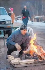  ?? EDDIE MOORE/JOURNAL ?? Manny Morales builds a fire to warm up on Delgado Street on Christmas Eve in Santa Fe last year.