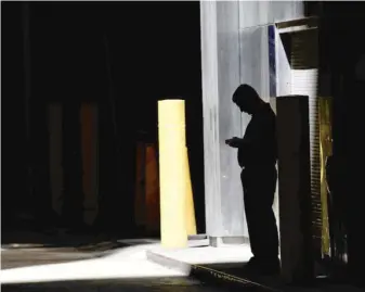  ?? AP FILE PHOTO ?? Aman checks his phone in an alley in downtown Chicago last year. A security researcher says a website flaw at a U. S. company could have allowed hackers to locate nearly any cellphone in the country.