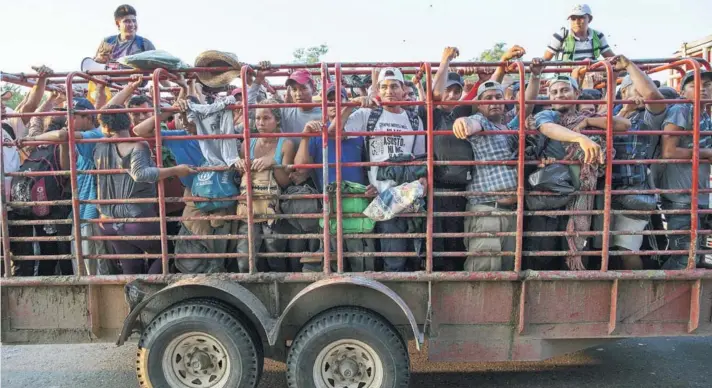  ??  ?? ► Migrantes viajan en un camión de ganado, mientras una caravana de miles de centroamer­icanos avanza a pie hacia la frontera de los Estados Unidos, ayer.