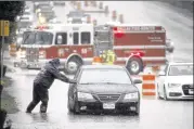  ?? TONY GUTIERREZ / ASSOCIATED PRESS ?? A Dallas Fire Rescue responder makes his way over to a stalled vehicle Friday to check on the driver still inside. The vehicle stalled after the road quickly flooded during a heavy rainfall.