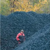  ?? PETR DAVID JOSEK/AP ?? A worker walks past piles of coal Nov. 11 at a selling point in Ostrava, Czech Republic. High energy prices have paved the way for coal’s comeback there.