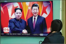  ?? SEONGJOON CHO / BLOOMBERG ?? A woman in Seoul, South Korea, last month watches a television screen showing a news broadcast about North Korean leader Kim Jong Un (left) traveling to Beijing to meet with President Xi Jinping of China.