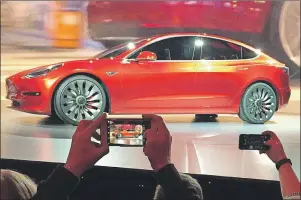  ?? AP PHOTO ?? In this March 31, 2016, photo, Tesla Motors unveils the new lower-priced Model 3 sedan at the Tesla Motors design studio in Hawthorne, Calif. Tesla said Monday the Model 3 will go on sale on Friday.