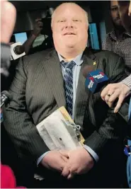  ?? DARREN CALABRESE/Postmedia News ?? Toronto Mayor Rob Ford waits for a security guard to clear a path through reporters at Toronto City Hall on Wednesday.