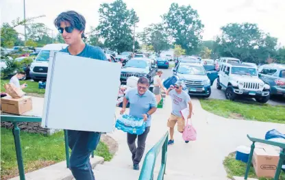  ?? CLOE POISSON PHOTOS/SPECIAL TO THE COURANT ?? Adil Shahzad, 18, of Darien, carries a mini-fridge to his dorm room in the Towers residence halls at the Uconn campus at Storrs during move-in day. His father, Shahzad Khawaja, follows. About 3,600 first-year students moved into dormitorie­s Friday.