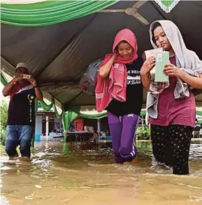  ?? PIC BY RASUL AZLI
SAMAD ?? Two brides-to-be Nur Syafiqah Hamzah, 21, (left) and Filzah Ghazali, 24, (right) moving their belongings to safer ground after floods in Kampung Sungai Putat yesterday.