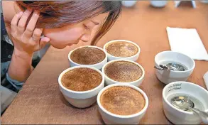  ?? PHOTOS BY CAI YANG / XINHUA ?? Top: Workers prepare coffee for guests at the Chongqing Coffee Exchange on April 13. Above: A guest smells coffee at the coffee trading center in Chongqing.