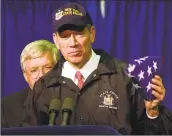  ?? Tony Gutierrez / AP ?? New York Gov. George Pataki holds an American flag, which earlier flew over the capitol, that was given to him by House Speaker Dennis Hastert, left, Oct. 1, 2001, in New York.
