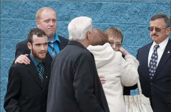  ?? Steph Chambers/Post-Gazette ?? Aaron Elchin of Cincinnati places his hand on the shoulder of his brother Zachery Bly of Chippewa as their mother, Dawna Bogolea Elchin Duez of Chippewa, hugs mourners as they attend a service for Air Force Staff Sgt. Dylan J. Elchin on Thursday. Funeral director Rick Murphy is at right.