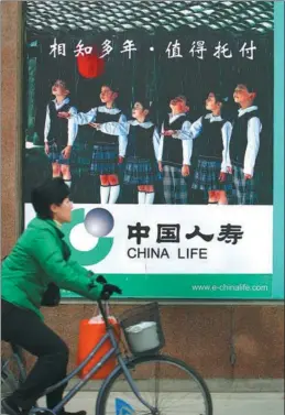  ?? AN XIN / FOR CHINA DAILY ?? A pedestrian cycles past a China Life Insurance billboard in Nanjing, Jiangsu province.
