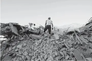  ?? [AP PHOTO] ?? A rescuer and a sniffer dog stand atop rubble Saturday in Amatrice in central Italy.