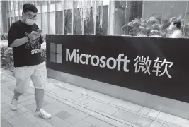  ?? NG HAN GUAN AP ?? A man walks by the Microsoft office in Beijing in 2020. The cyberthrea­ts from Beijing disclosed on Monday included a ransomware attack.