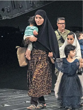  ??  ?? An Afghan family, carrying a few possession­s and young children, board a military plane full of refugees, above and below, at Kabul airport yesterday