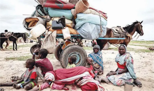  ?? File / Reuters ?? ↑ A displaced Sudanese family sit beside their belongings while waiting to be registered by UNHCR upon crossing the border between Sudan and Chad in Adre.