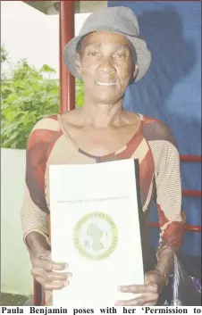  ?? (Ministry of the Presidency photo) ?? Paula Benjamin poses with her ‘Permission to Occupy State Lands’ document, which she received yesterday from Minister of State, Joseph Harmon