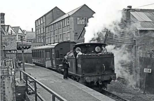  ?? ?? Watching brief: The driver of Class 1F No. 41748 eyes photograph­er Dick Riley while his fireman has a chat with the train guard at Dursley, Gloucester­shire, on September 21, 1955, in a photograph from Midland Archive Volume I. Other than the crew on the footplate of the 71-year-old ‘half-cab’ 0-6-0T and the guard, there is no sign of life, although a bicycle leaning against the station fence indicates there may be a passenger on board the single coach. TRANSPORT TREASURY/R C RILEY