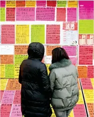  ?? Photo: VCG ?? Jobseekers look at the ads and informatio­n posted on the wall at a job market in Qingdao, Shandong province, earlier this year.