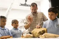  ?? Ryan Michalesko/The Dallas Morning News via AP ?? ■ Under the supervisio­n of paleontolo­gist Ron Tykoski, third from left, Angel Perez, left, 10, Enely Torres, 10, and Rafael Fernandez, 9, try their hand at removing a fossil from stone during a ribbon cutting for the new Paleo Lab in the Perot Museum of Nature and Science on Tuesday in Dallas.