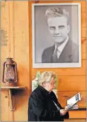  ??  ?? ABOVE: A woman at the viewing reads a brochure under a photo of a young Billy Graham.