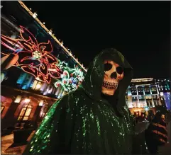  ?? (AP/Marco Ugarte) ?? A person dressed as La Santa Muerte poses for a photo Dec. 9 in Mexico City’s main square as Christmas lights shine.