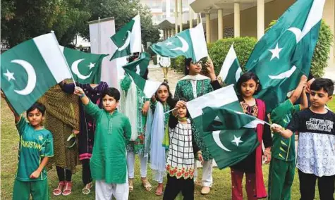  ?? Ahmed Ramzan/Gulf News ?? ■ Pakistani children wave national flags during the National Day celebratio­ns at the Pakistan Consulate in Dubai yesterday.