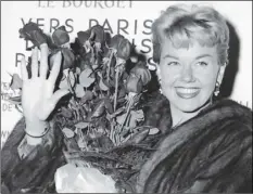  ??  ?? In this April 15, 1955, file photo, American actress and singer Doris Day holds a bouquet of roses at Le Bourget Airport in Paris, France after flying in from London. AP PHOTO