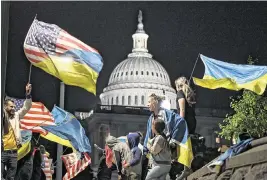  ?? KENNY HOLSTON NYT ?? People who stand in solidarity with Ukraine wave flags and hold signs outside the U.S. Capitol April 23. Some Republican­s who backed the aid for Ukraine encountere­d little resistance from voters, who were far more willing to embrace it than their right-wing colleagues.