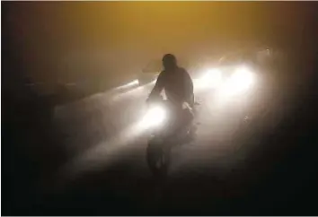  ??  ?? Leading lights A man rides a motorcycle through a road amid dense fog on a cold winter night in New Delhi on Sunday. Cold wave conditions continue across most parts of North India.
Reuters