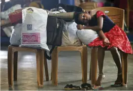  ?? — AP ?? A girl rests on her baggage at a flood relief camp set up inside a school in Kochi on Thursday.