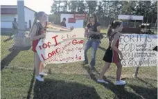 ?? RANDY EDWARDS, THE BEAUMONT ENTERPRISE, VIA AP ?? Middle-school cheerleade­rs decorate the field at Kountze (Texas) High School with banners sporting biblical verses last month.