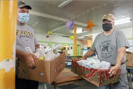 ?? Christian Snyder/Post-Gazette ?? Mitch Bassi, left, of Gibsonia, and Mark Zaitsoff, of Squirrel Hill, pick up meals Wednesday from Earthen Vessels Outreach in Bloomfield to distribute in partnershi­p with the Greater Pittsburgh Community Food Bank.