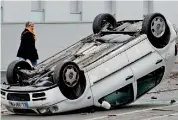  ??  ?? A car that was vandalized by students sits upside down on a street near a technical school in France