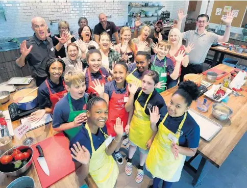  ?? JOE BURBANK/ORLANDO SENTINEL ?? Sixth-graders from Orlando Junior Academy pose for a group photo with local celebrity chefs and culinary experts before the Iron Chef Jr. competitio­n at the Edible Education Experience, held at the Emeril Lagasse Foundation Kitchen House & Culinary Garden in College Park.