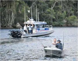  ?? AP ?? Fishermen guide their boat past a police vessel near the spot where a seaplane crashed Sunday into the Hawkesbury River, north of Sydney, Australia.