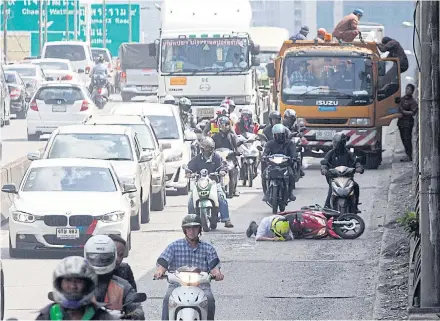  ?? PAWAT LAOPAISARN­TAKSIN ?? Motorcycli­sts drive along a flyover passing over the busy Sunthorn Kosa intersecti­on on Sept 25, 2017, when one falls over after hitting a pothole, injuring his leg. City workers later rushed to fix the potholes.