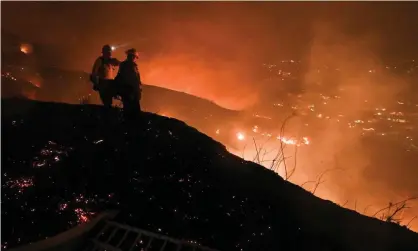  ?? Photograph: Robyn Beck/AFP/Getty Images ?? Firefighte­rs look out over a burning hillside in Yorba Linda, California, on 27 October 2020.