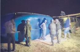  ?? MOSA’AB ELSHAMY/AP ?? Smugglers lift a fishing boat intended to carry migrants to the Canary Islands last month in a remote spot near the town of Dakhla in Western Sahara.