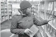  ?? Mark Lennihan / Associated Press ?? Fanta Renner picks out books for her son at an Amazon Books in New York. Investors expect improved shopping for the holidays.