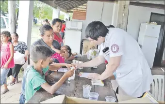  ??  ?? Un médico entrega remedios a miembros de una familia damnificad­a por la riada.