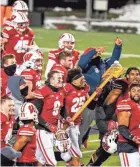  ?? ASSOCIATED PRESS ?? Eric Burrell carries Paul Bunyan's Axe as his Wisconsin teammates celebrate after defeating Minnesota on Saturday in overtime.