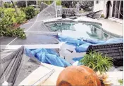  ?? PHOTOS BY THE NEWS-PRESS VIA AP ?? Cape Coral residents (background) assess the damage to their pool enclosure after a tornado touched down in Cape Coral on Saturday.