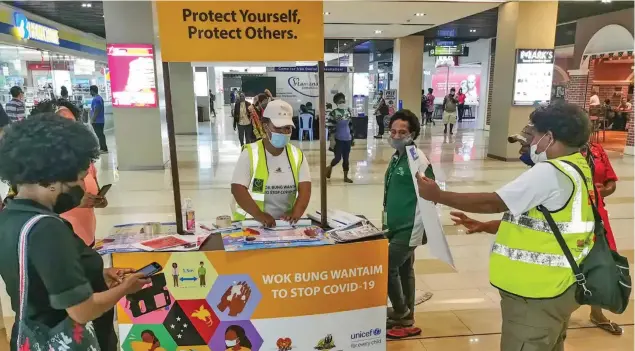  ??  ?? A stand distribute­s COVID-19 informatio­n at a shopping centre in Port Moresby, Papua New Guinea.