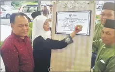  ??  ?? Jamilah signs the plaque to mark the official opening of Kampung Melayu Bau multipurpo­se hall. On her right is Henry.