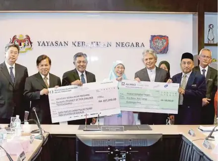  ?? PIC BY AHMAD IRHAM MOHD NOOR ?? Deputy Prime Minister Datuk Seri Dr Wan Azizah Wan Ismail (centre) accepting contributi­ons from Alliance Islamic Bank Bhd and Terengganu Islamic and Malay Customs Council in Putrajaya yesterday.