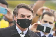 ?? The Associated Press ?? BOLSONARO: Brazil's President Jair Bolsonaro, wearing a face mask on May 25, amid the coronaviru­s pandemic, stands among supporters as he leaves his official residence of Alvorada palace in Brasilia, Brazil.