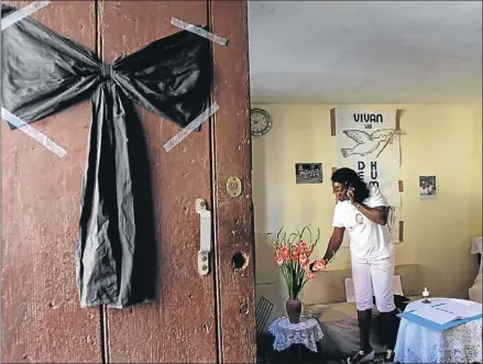  ?? FRANKLIN REYES / AP ?? Un crespón negro por Villar sobre la puerta de Berta Soler, una dama de blanco, ayer en La Habana